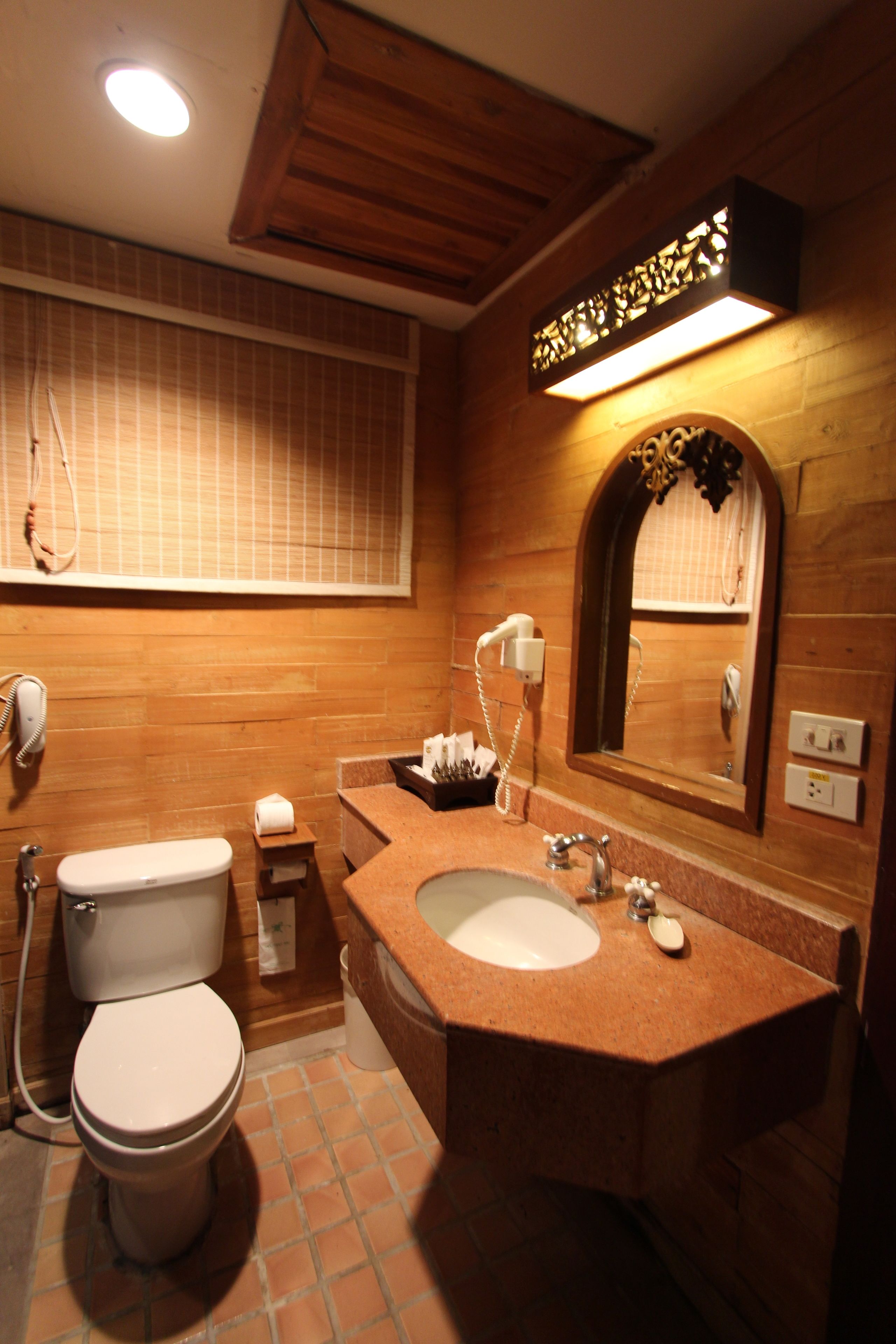 A bathroom with a wooden vanity, a sink, a mirror, a toilet, and a shower.