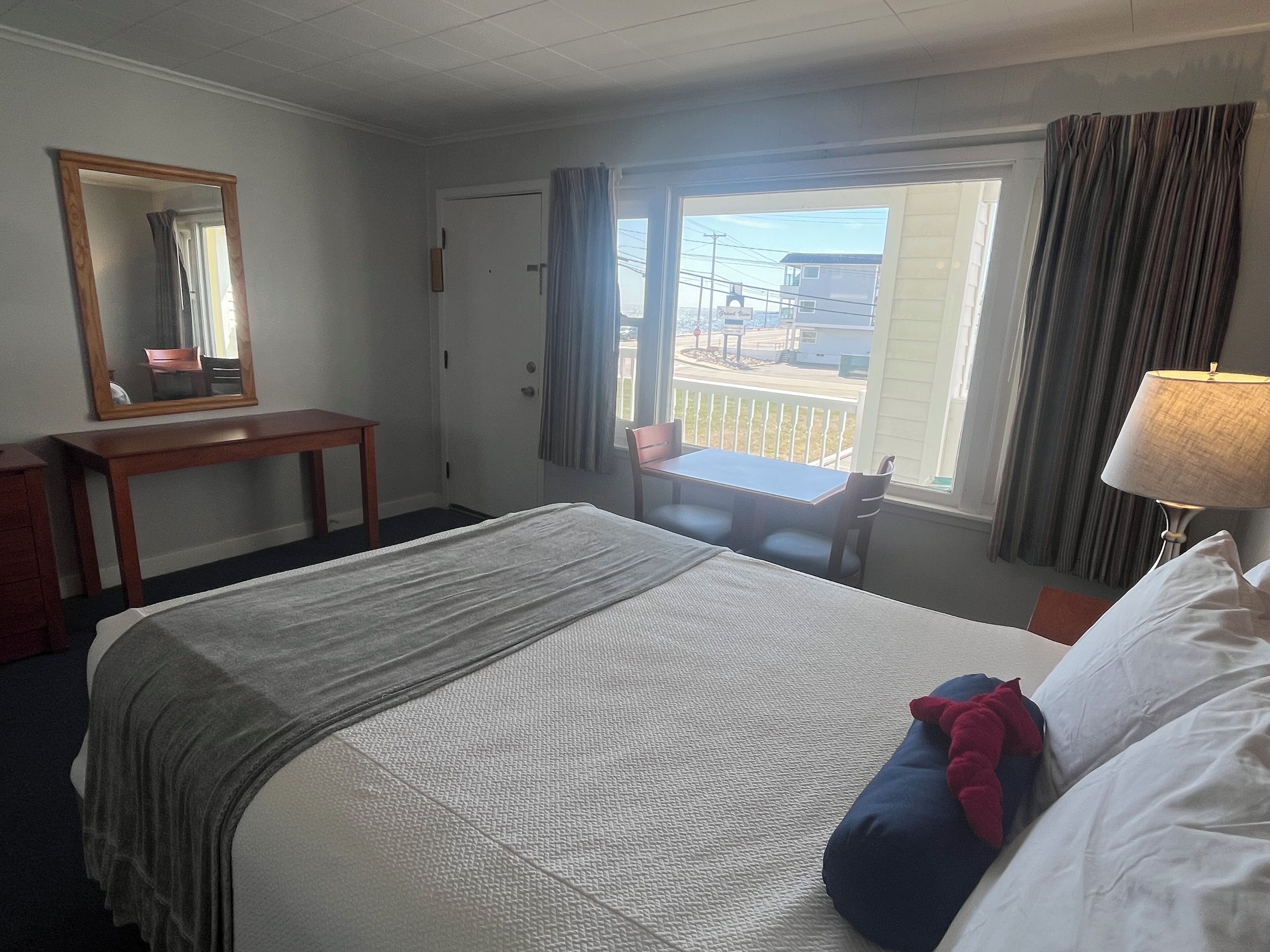 Een hotelkamer met een bed, een bureau, een stoel, een raam met gordijnen en een lamp.