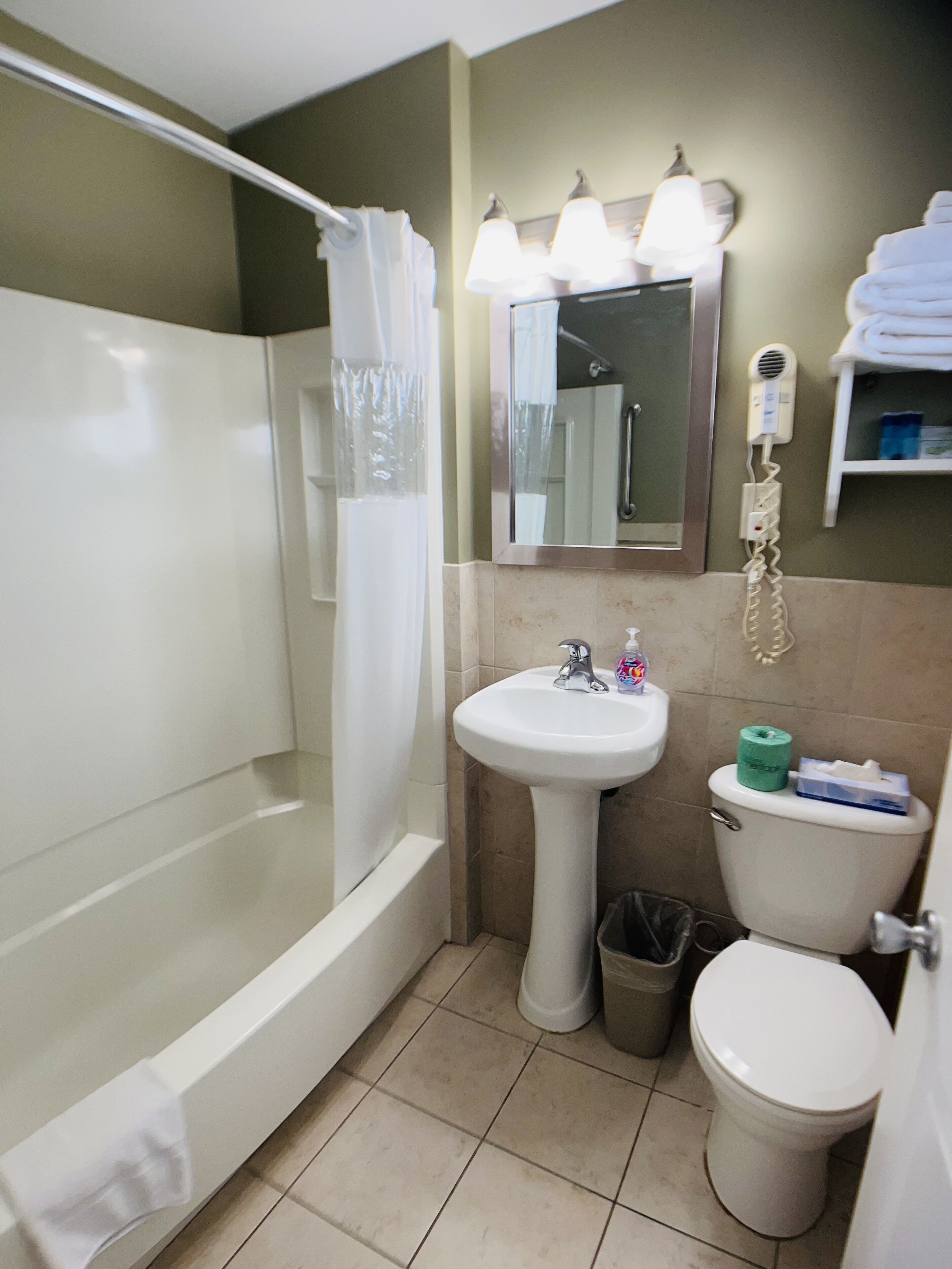 Un baño con ducha, lavamanos, inodoro y un espejo con iluminación.