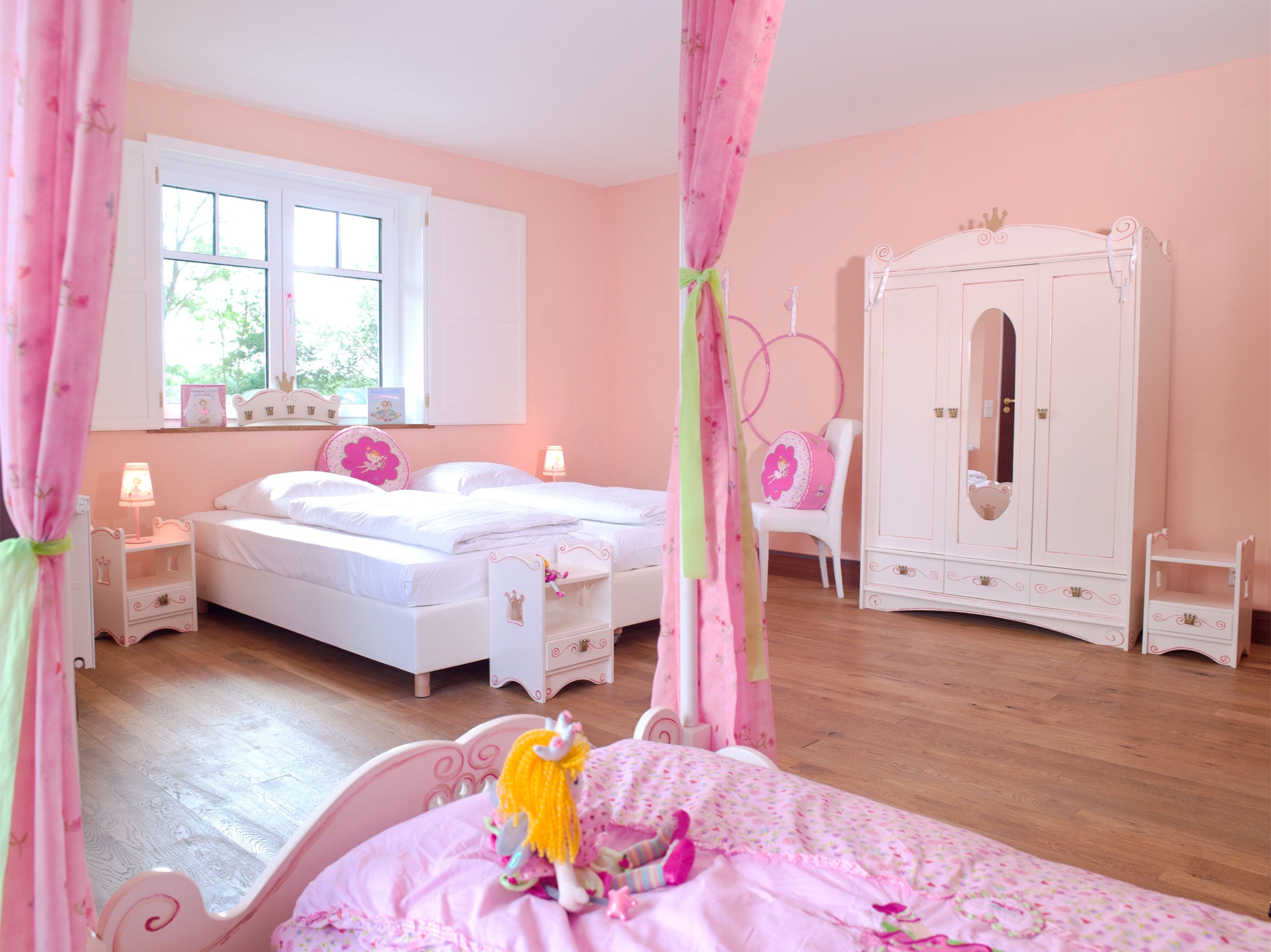 A pink-themed bedroom with a bed, a wardrobe, and a chair.