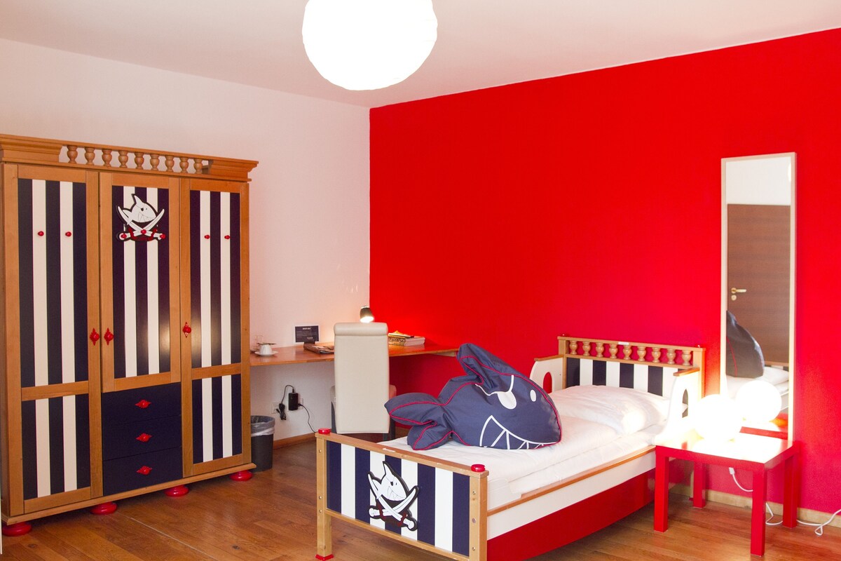 Un dormitorio con cama, escritorio, armario y espejo.