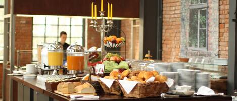 A buffet setup with various food items, a beverage station, and a candle centerpiece.