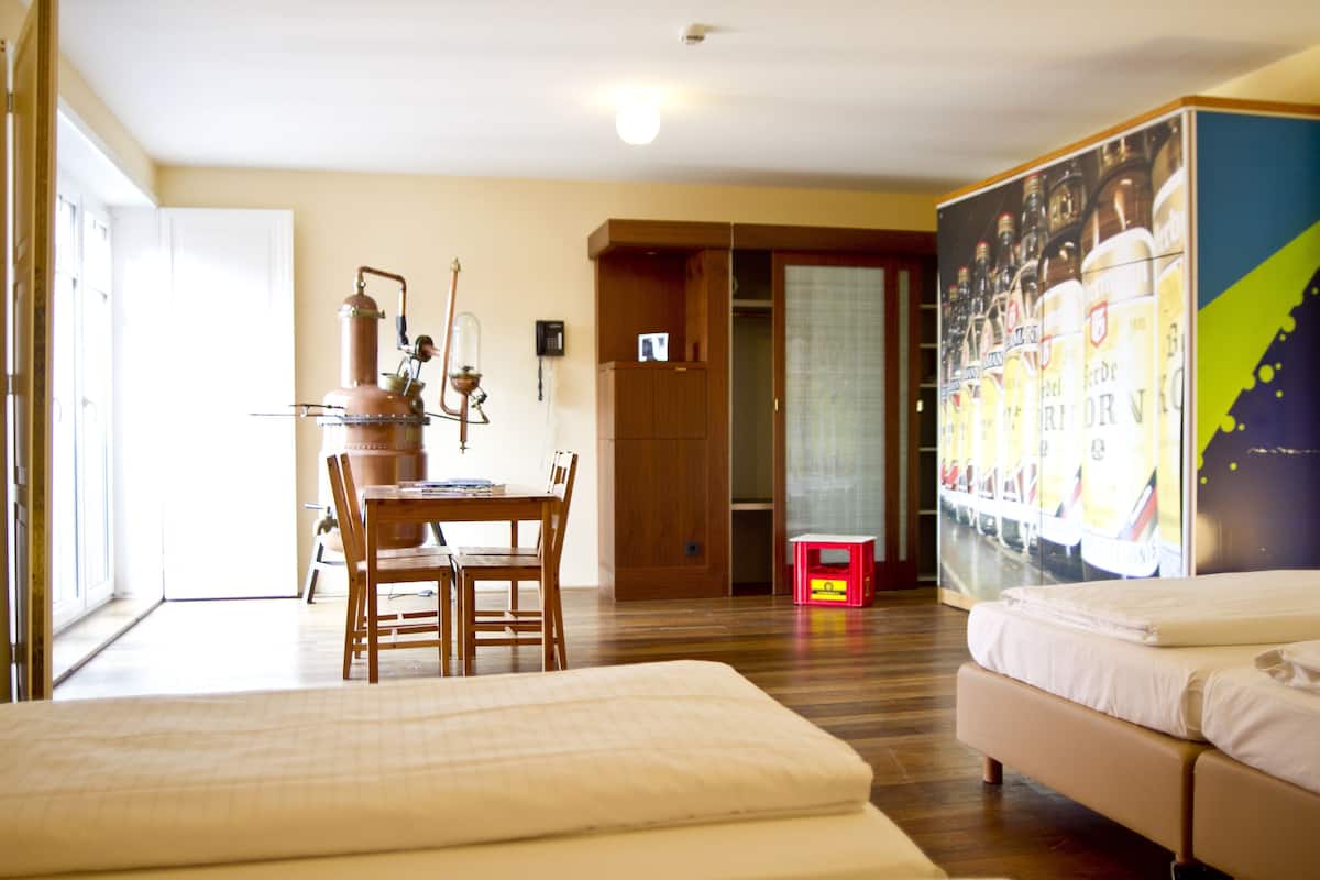 Une chambre d’hôtel avec un lit, un bureau et une chaise, une petite table et un grand tableau accroché au mur.