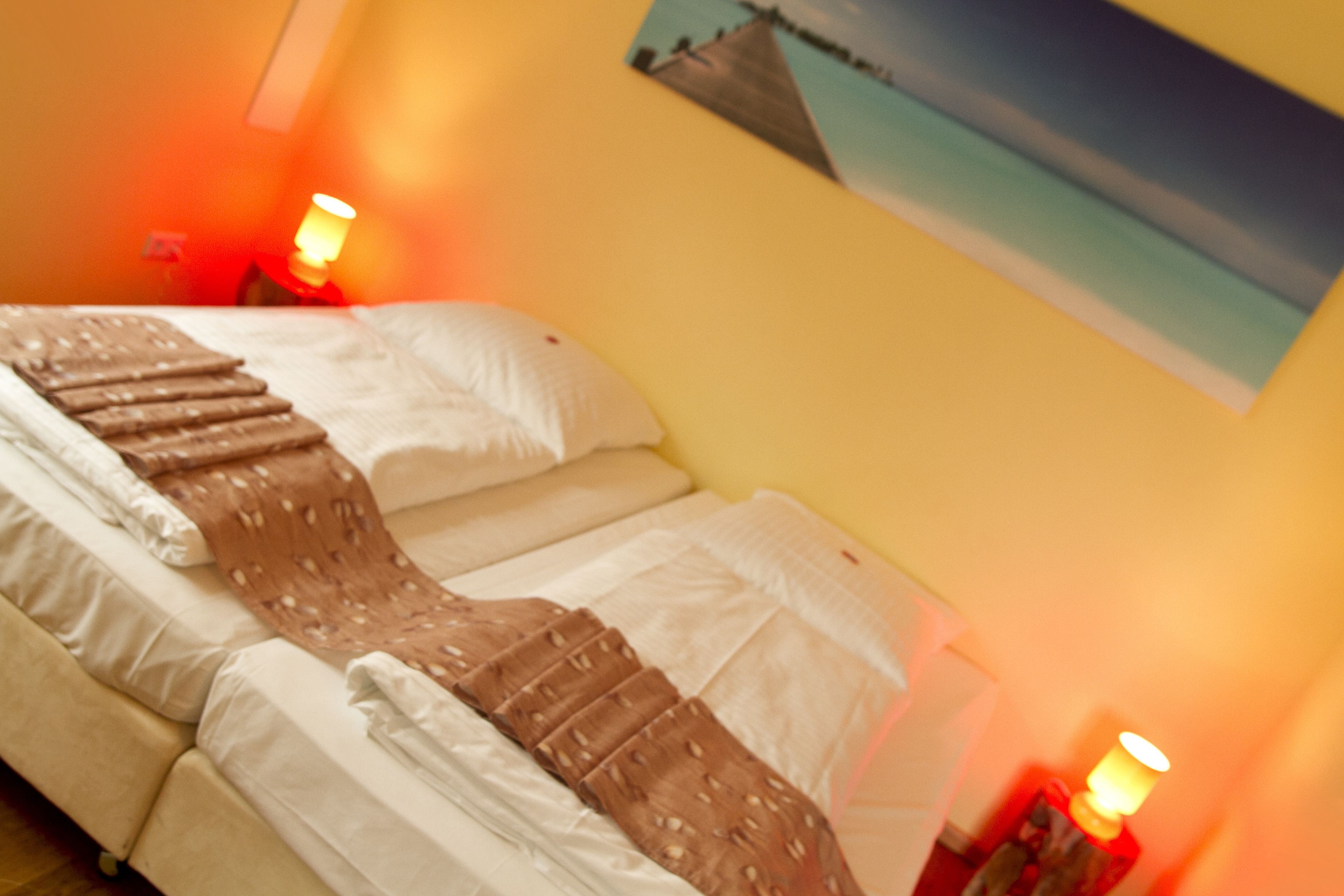 Une chambre d’hôtel avec un lit, des oreillers et une couverture. Il y a deux tables de chevet avec des lampes.