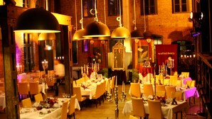 Un restaurante con varias mesas dispuestas para comer, una pared de ladrillo al fondo y lámparas colgantes.