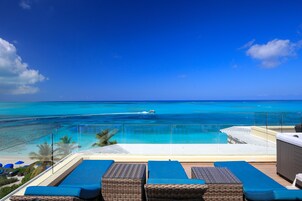 Un área junto a la piscina con sillones de descanso, un jacuzzi y vistas al océano.