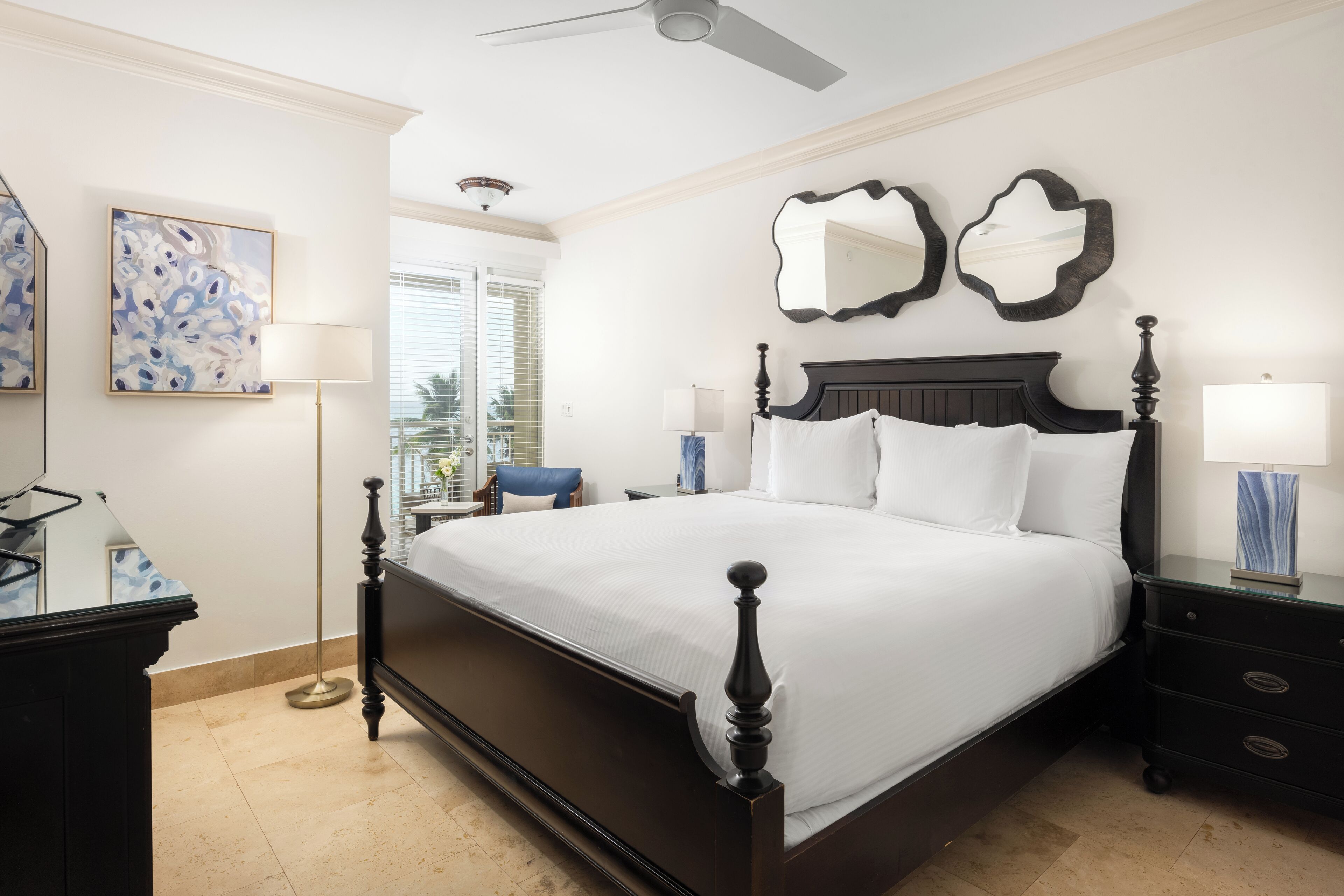A neatly arranged bedroom with a large bed, a nightstand, a dresser, and a ceiling fan.