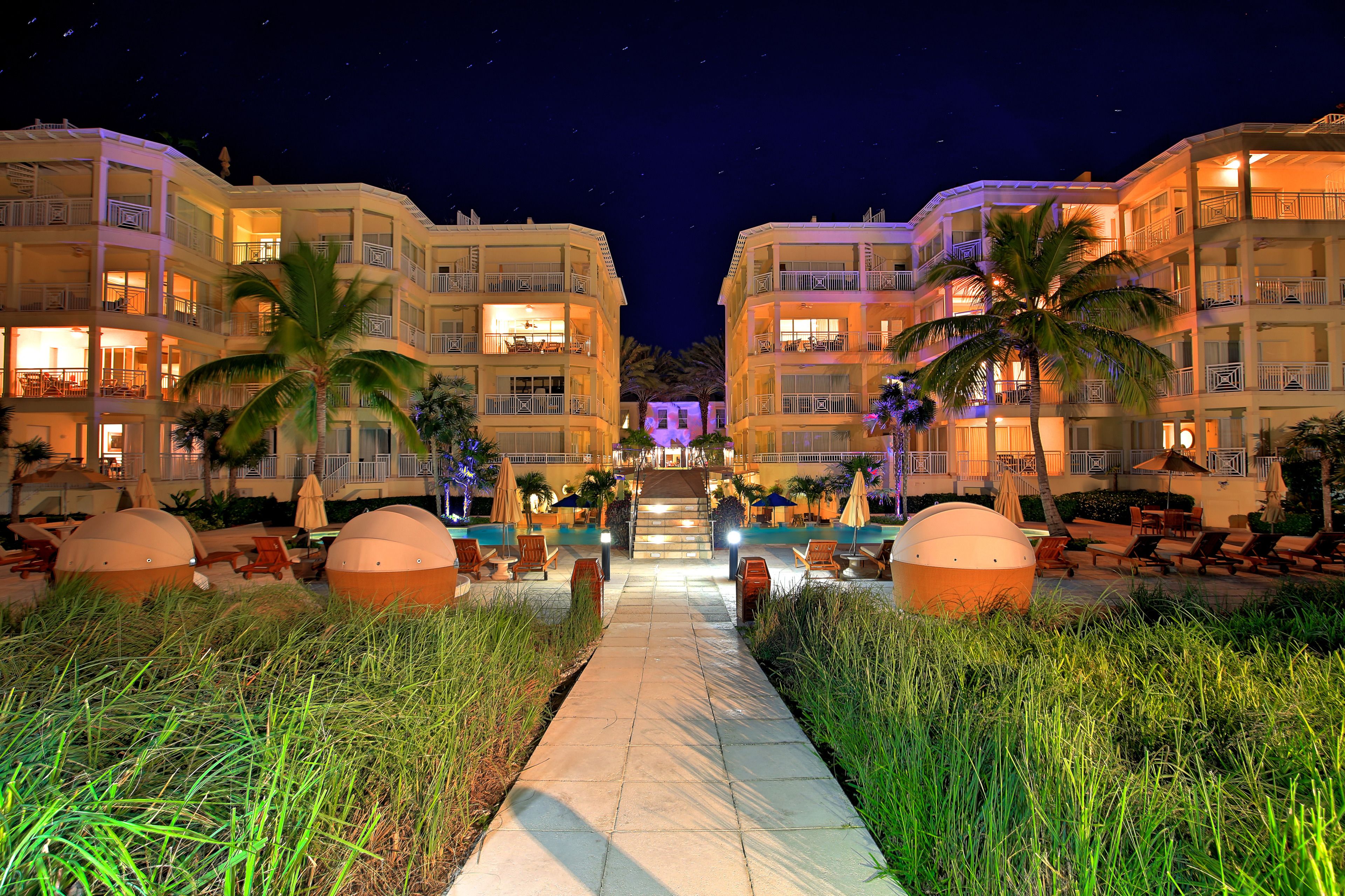 A hotel with multiple floors, outdoor seating areas, and palm trees.