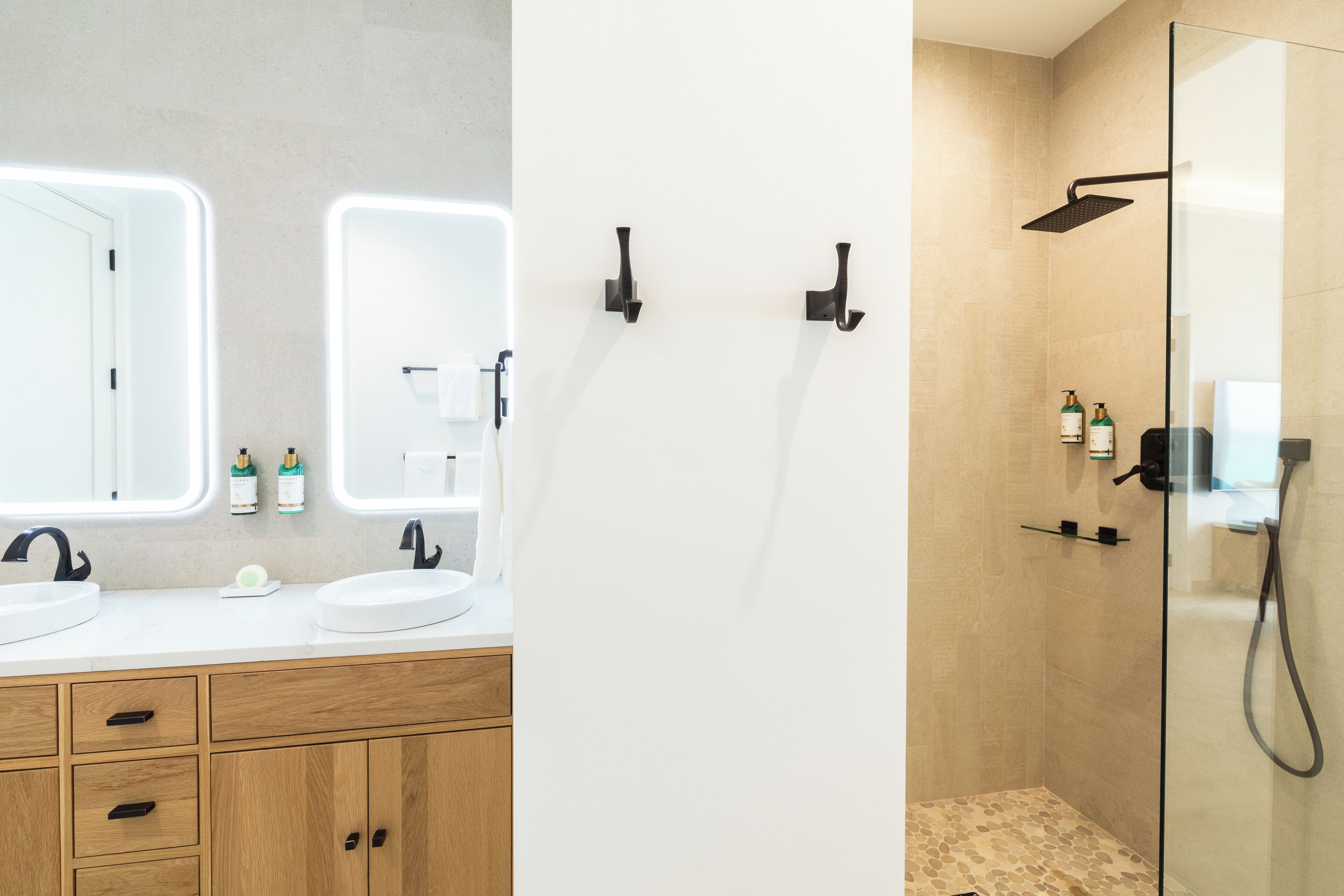 A modern bathroom with two sinks, a glass shower enclosure, and wooden cabinetry.
