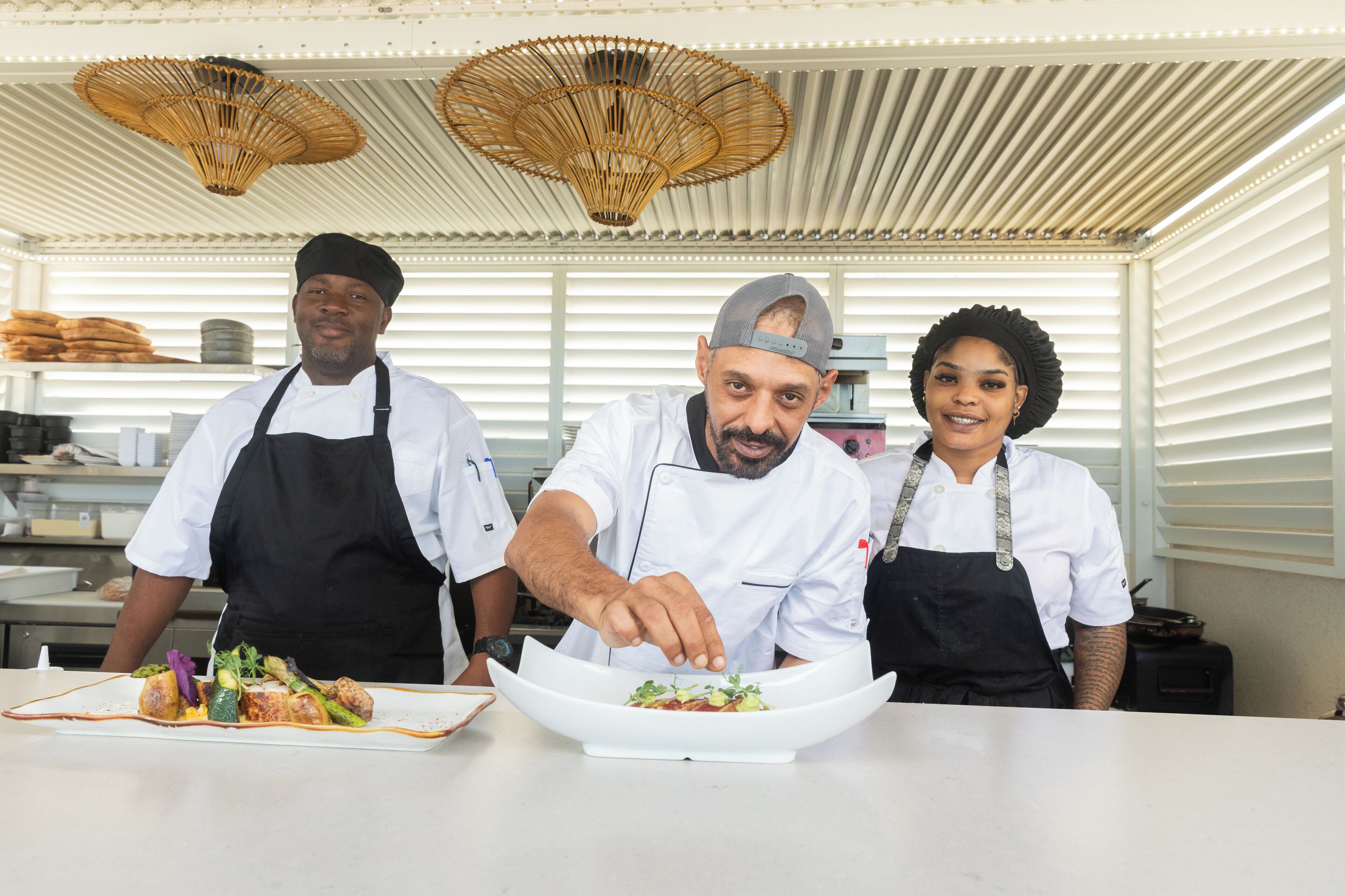 Trois chefs sont dans une cuisine et préparent des plats.