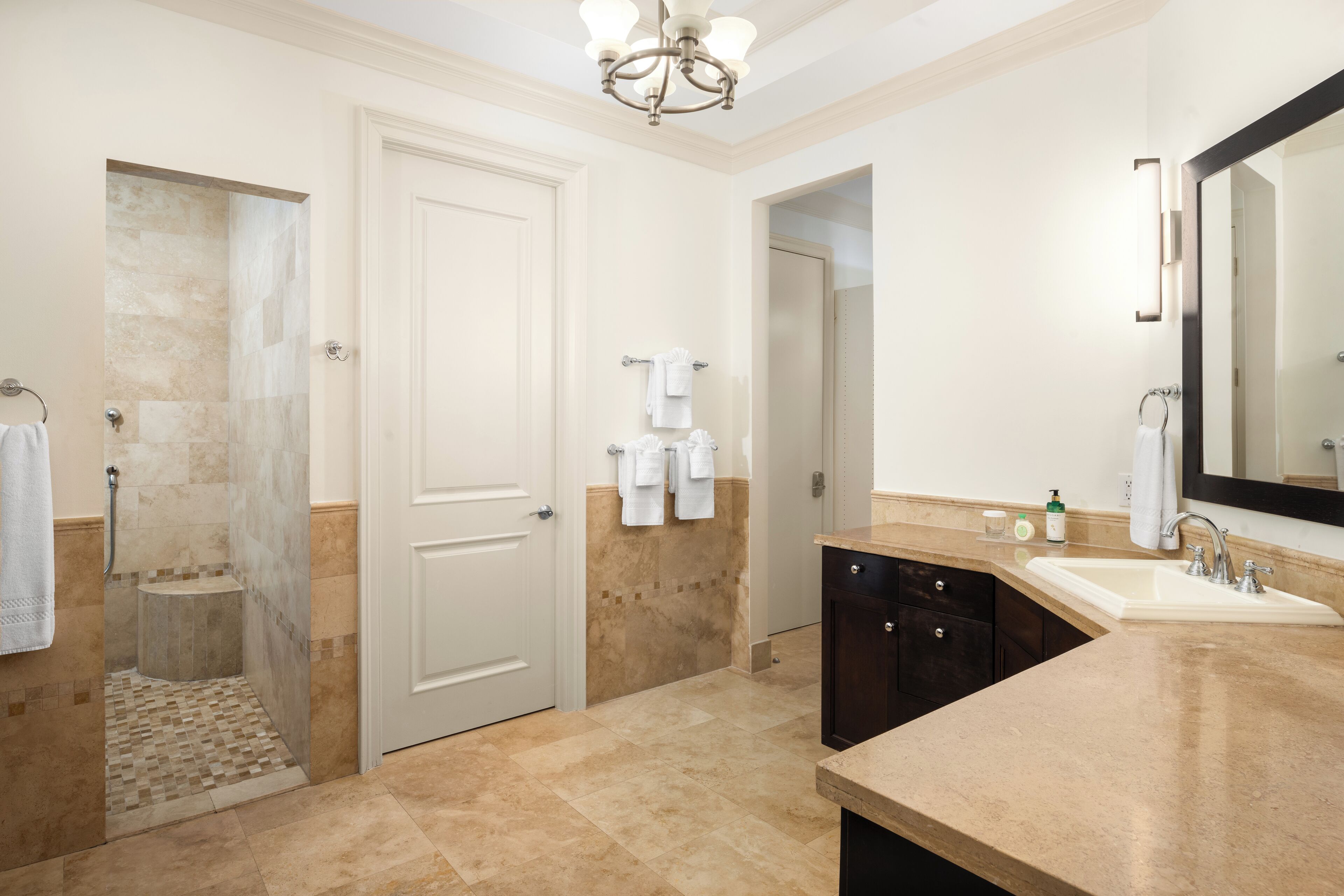 A modern bathroom with a shower, sink, and large mirror.