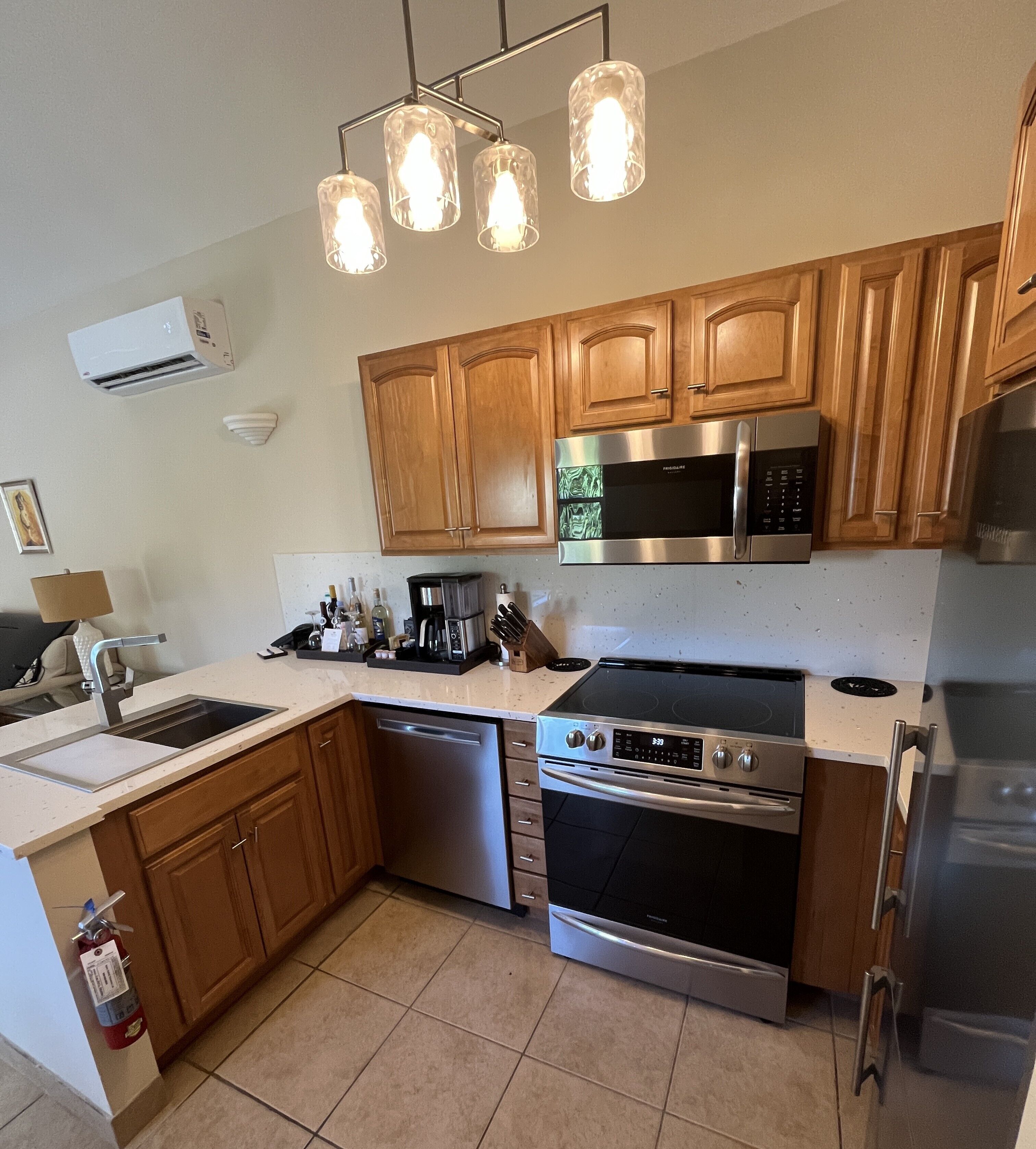 A modern kitchen with wooden cabinets, a stainless steel microwave, a built-in oven, and a dishwasher.