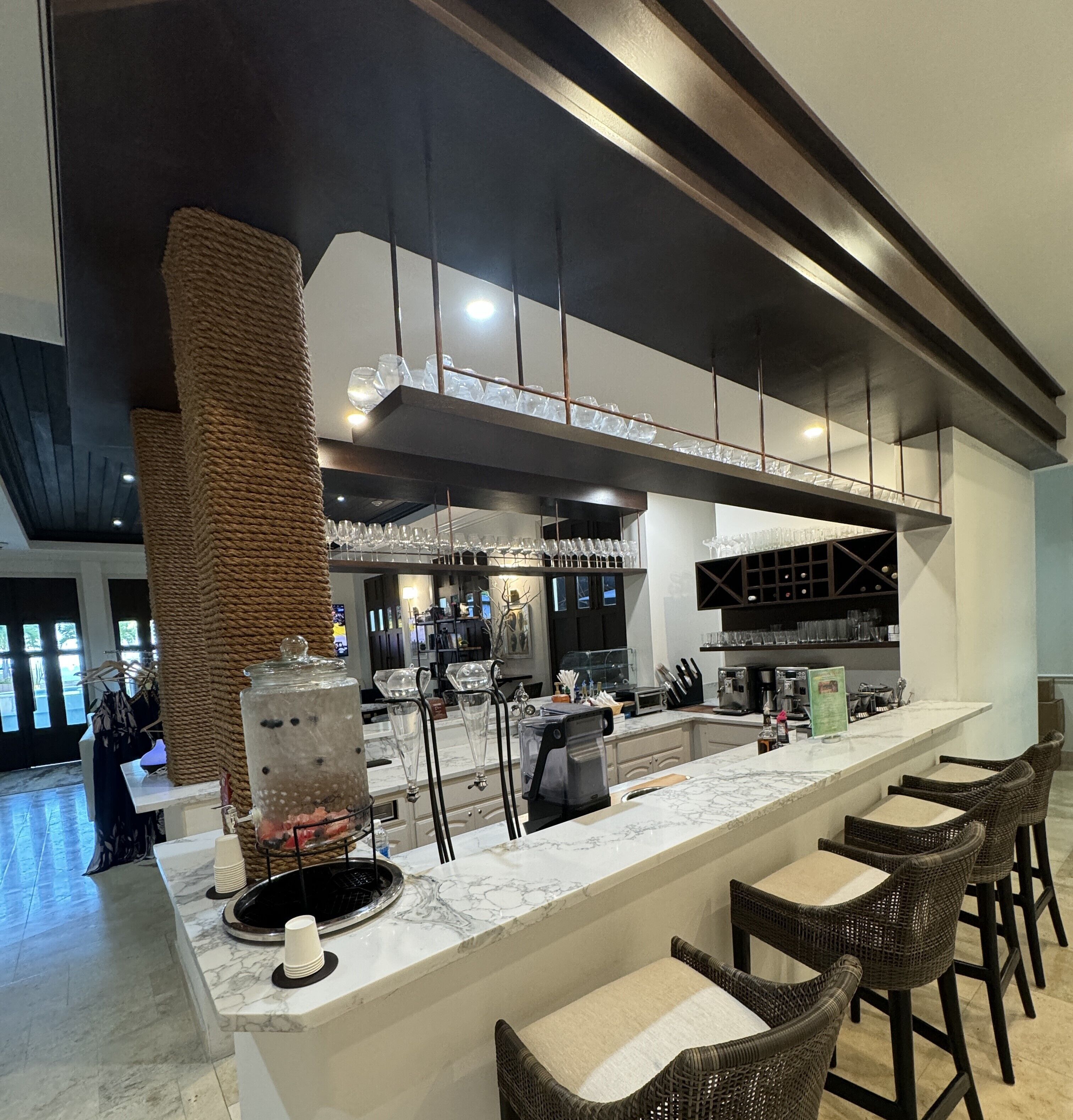 A modern bar area with a marble countertop, bar stools, and a large decorative column.