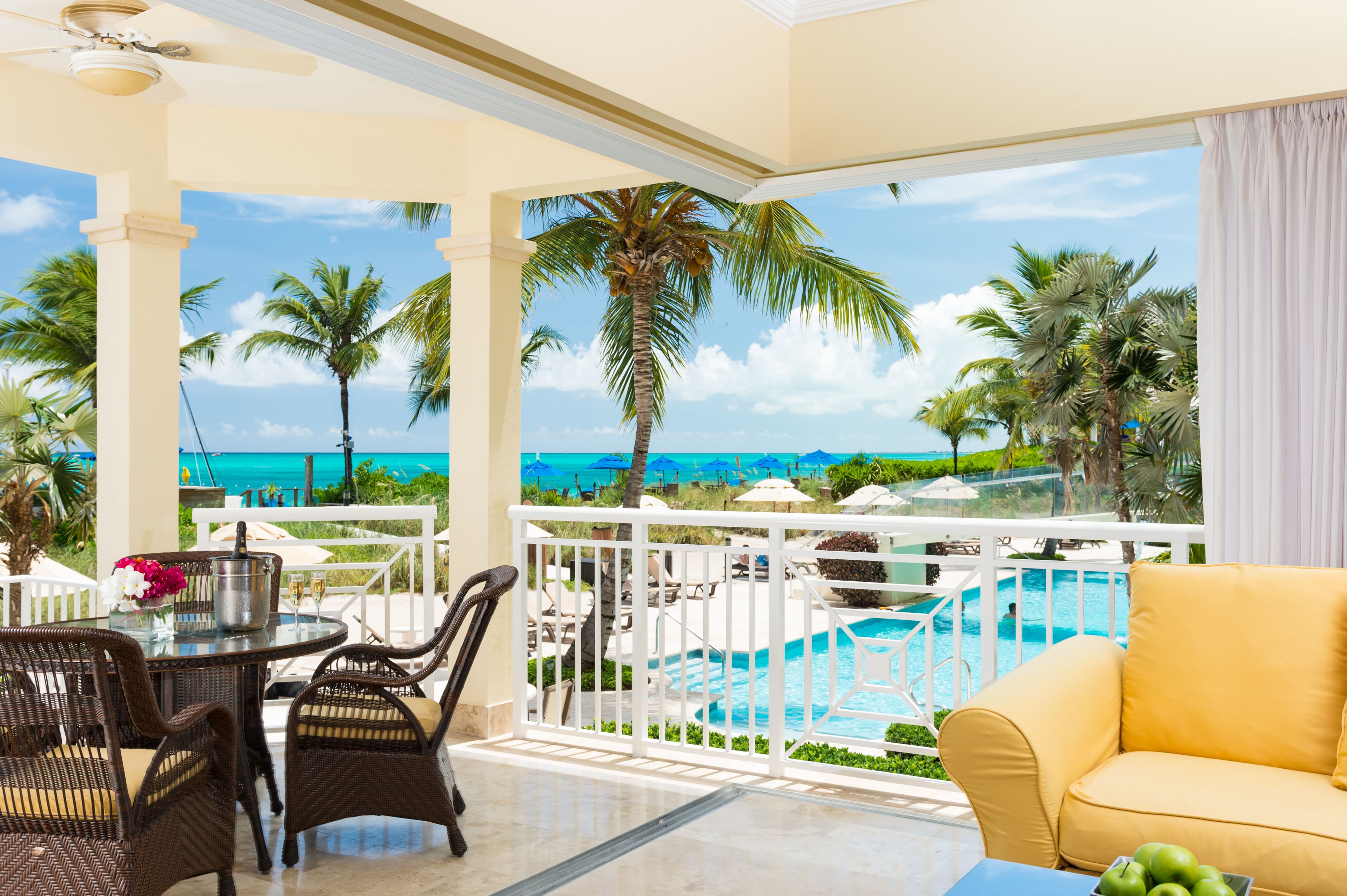 Ein Balkon mit Blick auf das Meer, ein Schwimmbad und Gartenmöbel.