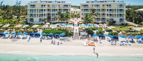 A beachfront hotel with multiple balconies, a pool area, and beach chairs.
