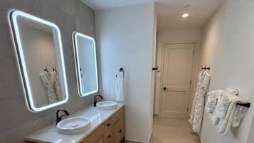 A modern bathroom with two sinks, a vanity, and a mirror with illuminated edges.