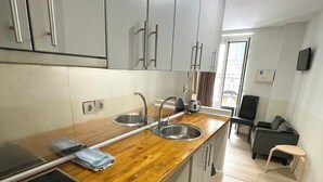 A modern kitchen with grey cabinets, stainless steel appliances, and a wooden countertop. - Apartamentos Mayor Centro (Madrid)