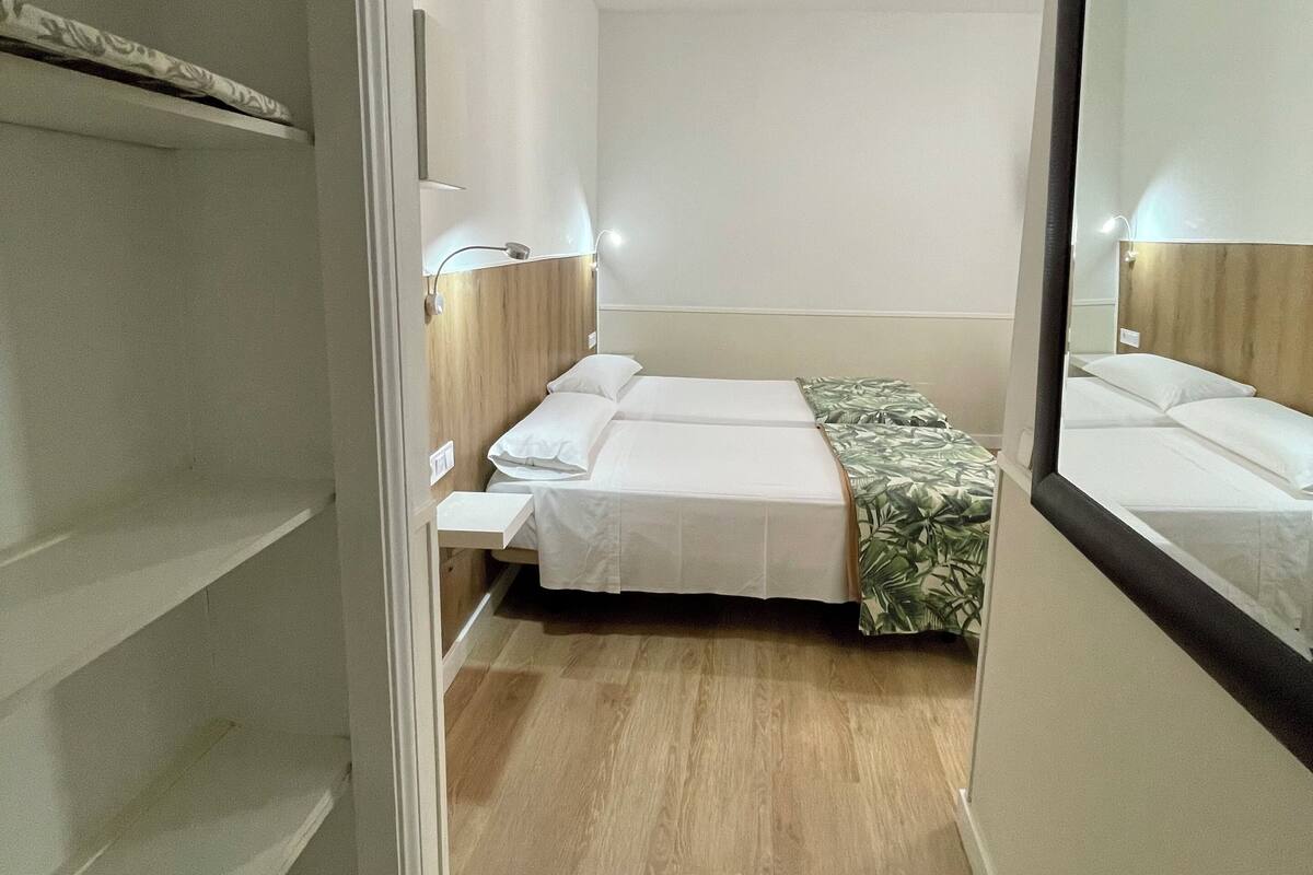 Un dormitorio con cama, mesitas de noche y un espejo.