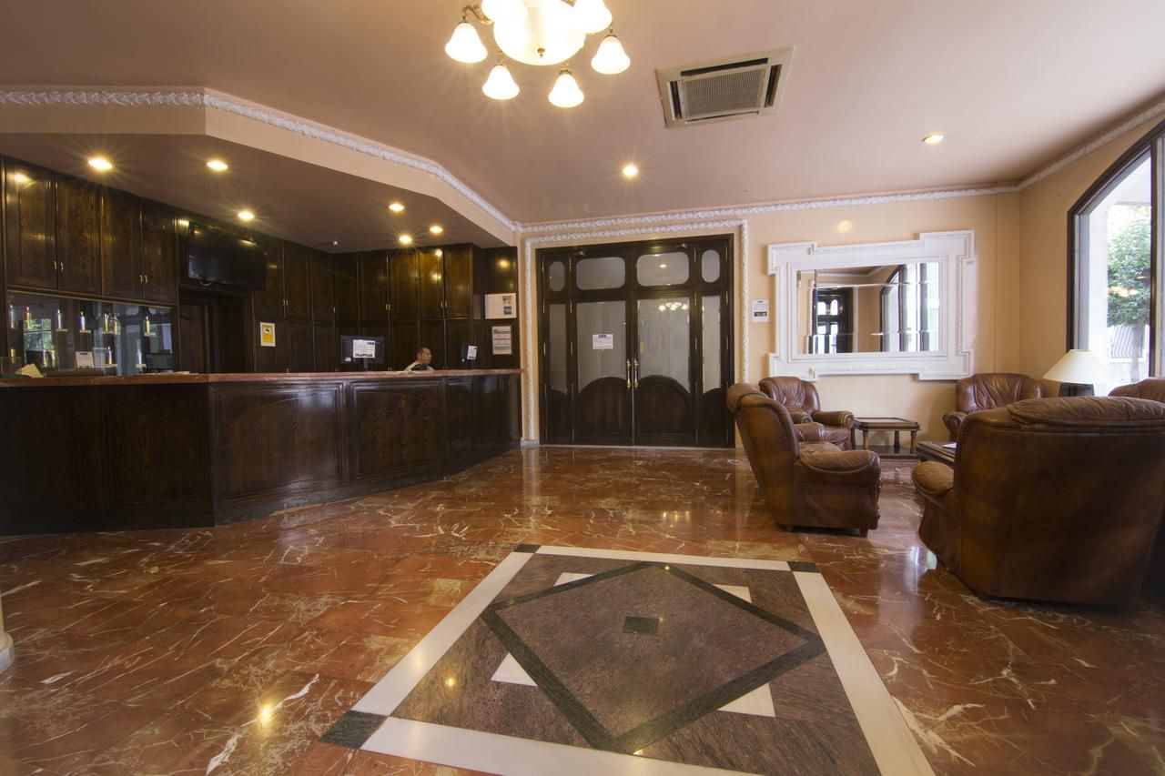 A lobby with a reception desk, leather armchairs, and a patterned floor.