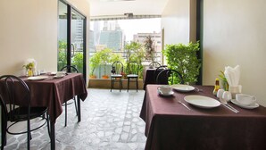 A dining area with two tables, chairs, and potted plants. - Bally Suite Silom (Bangkok)