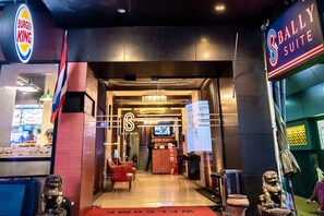 The entrance to a hotel with a sign for 'Bally Suite' and a Burger King across the street. - Bally Suite Silom (Bangkok)