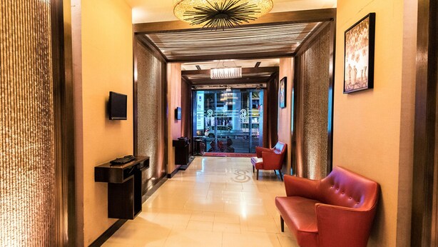 A hotel lobby with a modern design, featuring a reception desk, seating area, and a view into the bar area. - Bally Suite Silom (Bangkok)