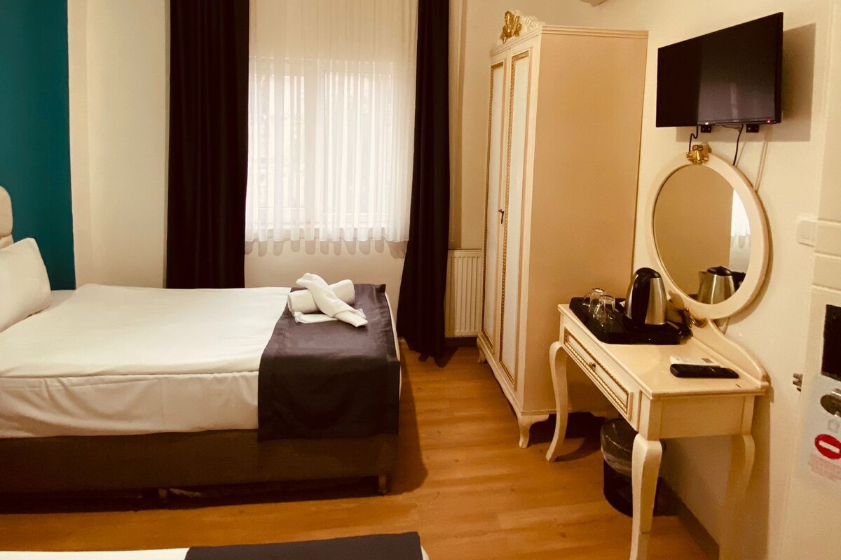 A hotel room with a bed, bedside table, mirror, and a television mounted on the wall.