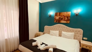 Una habitación de hotel con una cama, una mesita de noche, una lámpara de pared y un cuadro.