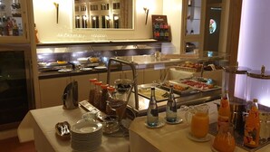 A buffet setup with various food items, beverages, and condiments.