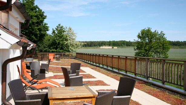 An outdoor patio with wicker furniture and a view of a golf course.
