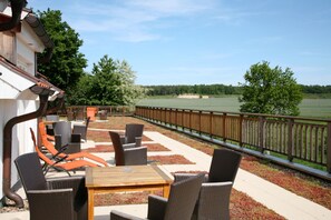 Een terras buiten met rieten meubilair en uitzicht op een golfbaan.
