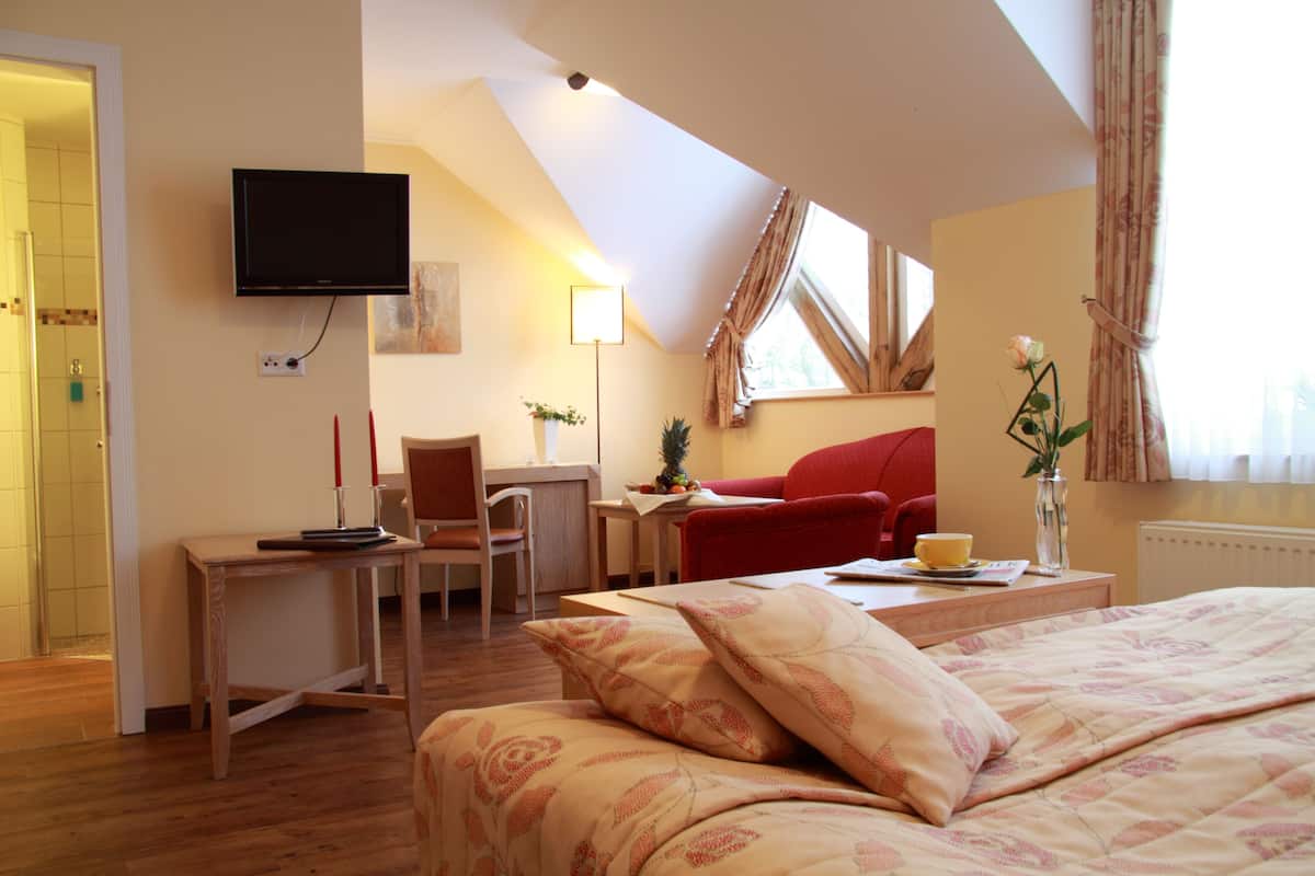 Ein Hotelzimmer mit Bett, Schreibtisch, Stuhl, Fernseher und einem Fenster mit Vorhängen.