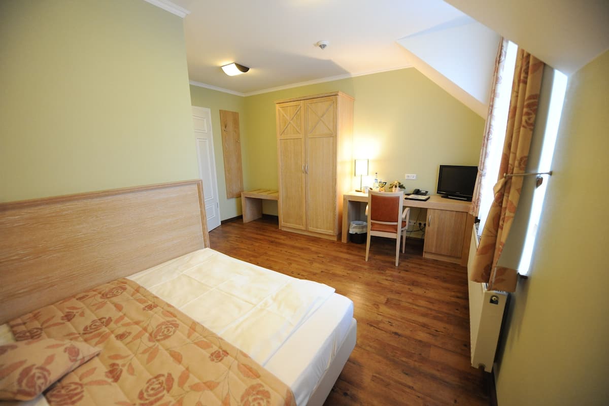Ein Schlafzimmer mit Bett, Schreibtisch mit Stuhl, Fernseher und Kleiderschrank.