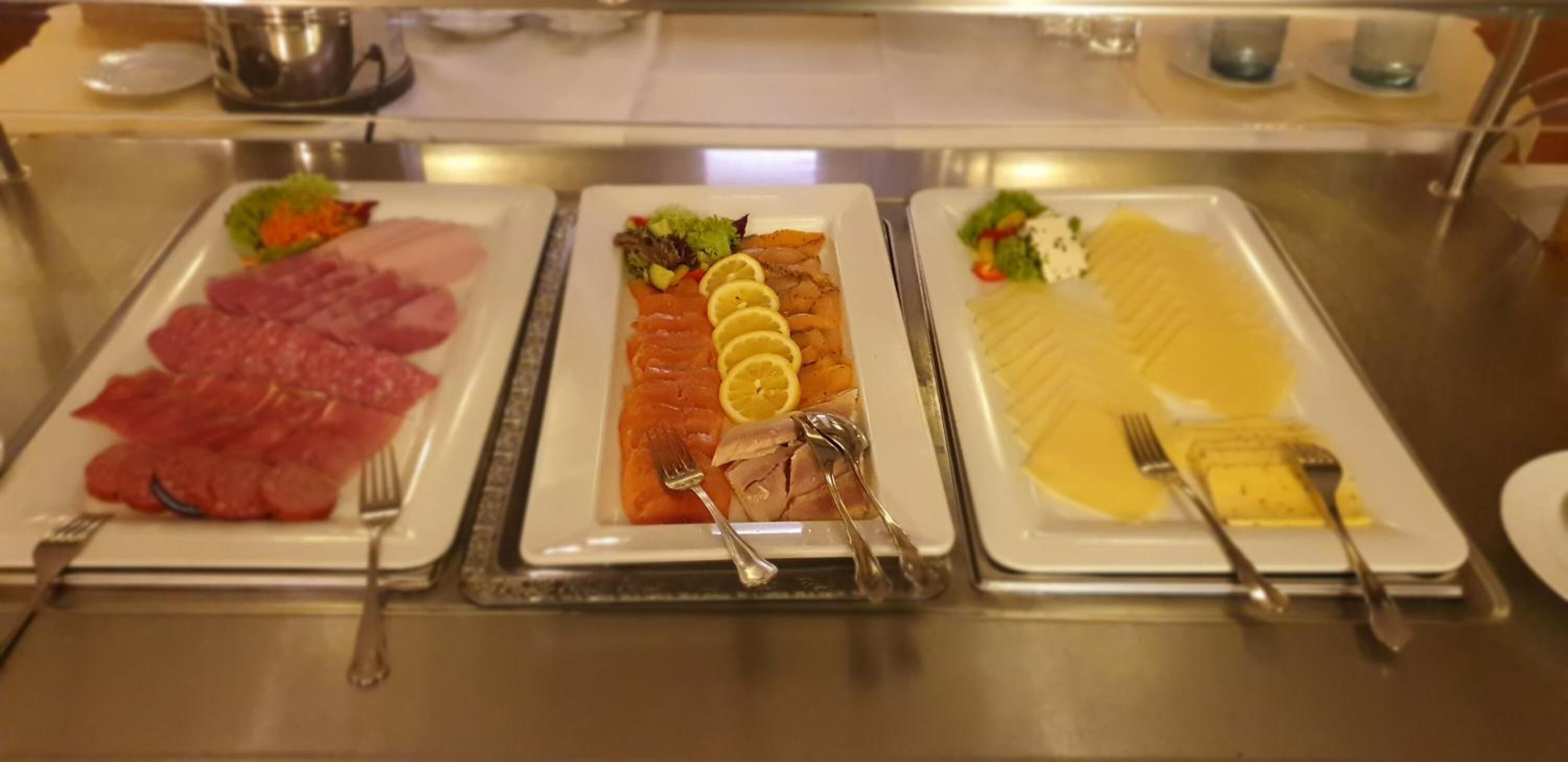A buffet with various food items including meats, fish, and vegetables.