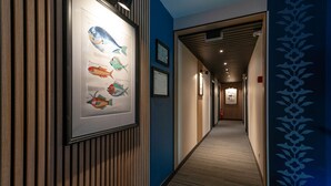 Un pasillo con ilustraciones enmarcadas de peces en la pared, un diseño de listones de madera a la izquierda y un revestimiento con estampado a la derecha.