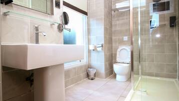A modern bathroom with a glass-enclosed shower, a white sink, and a toilet.