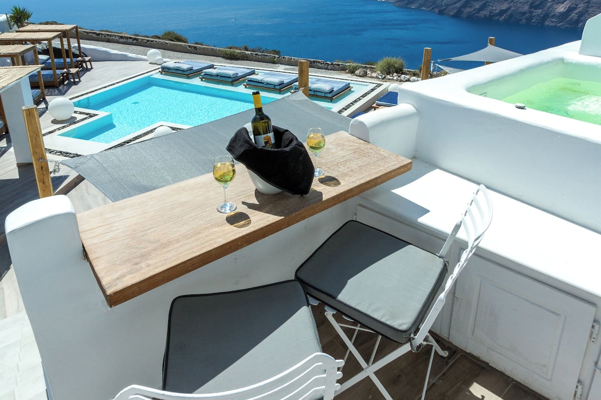A rooftop terrace with a pool, seating, and a bottle of wine.
