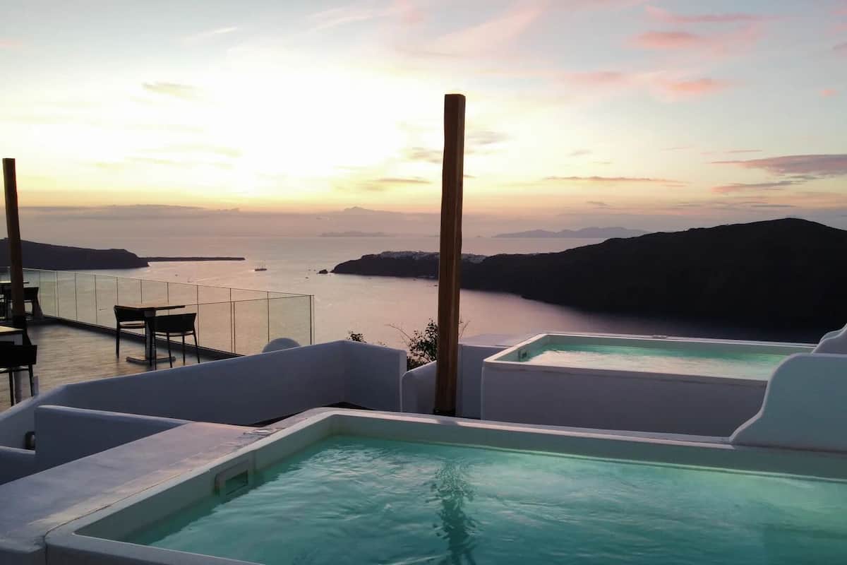 A rooftop pool with a view of the sea and a sunset.