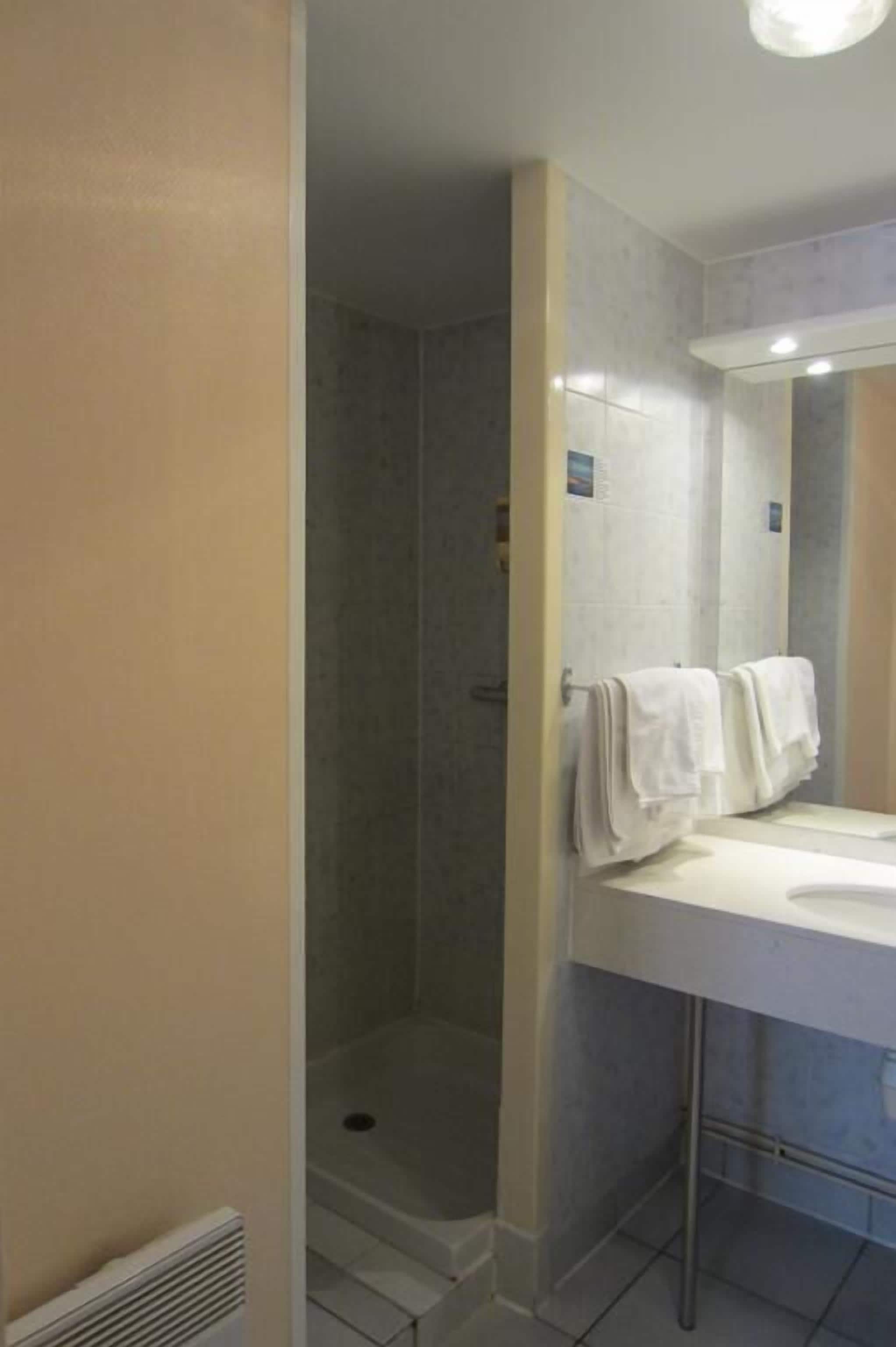 Une salle de bain avec une douche, un lavabo et un miroir.
