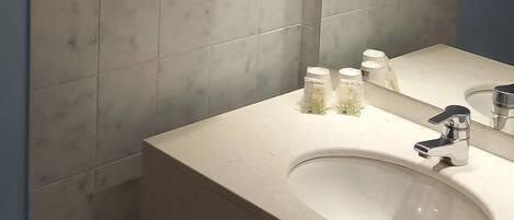 A bathroom with a white sink, a mirror, and towels hanging on a rack.