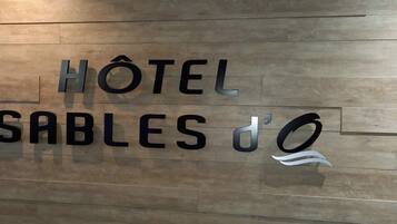 Pared de madera con el texto "HÔTEL SABLES d'O" que indica el nombre del hotel.