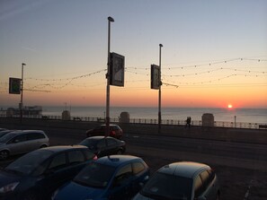 A sunset view from a coastal road with cars parked along the side and a pedestrian walkway. - Tiffanys Hotel (Blackpool)