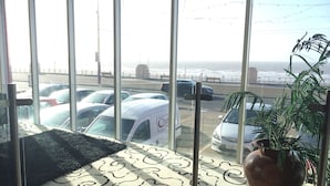Une pièce dotée de grandes fenêtres donnant sur un parking et l’océan.