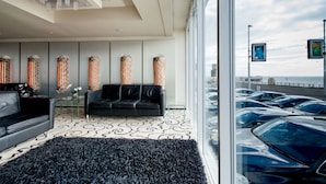 Un intérieur moderne avec un canapé noir, un tapis à motifs et de grands vases décoratifs.