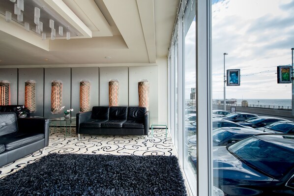 Un interior moderno con un sofá negro, alfombra estampada y altas jarrones decorativos.