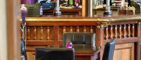 A bar area with wooden furniture, a clock, and multiple beer taps.