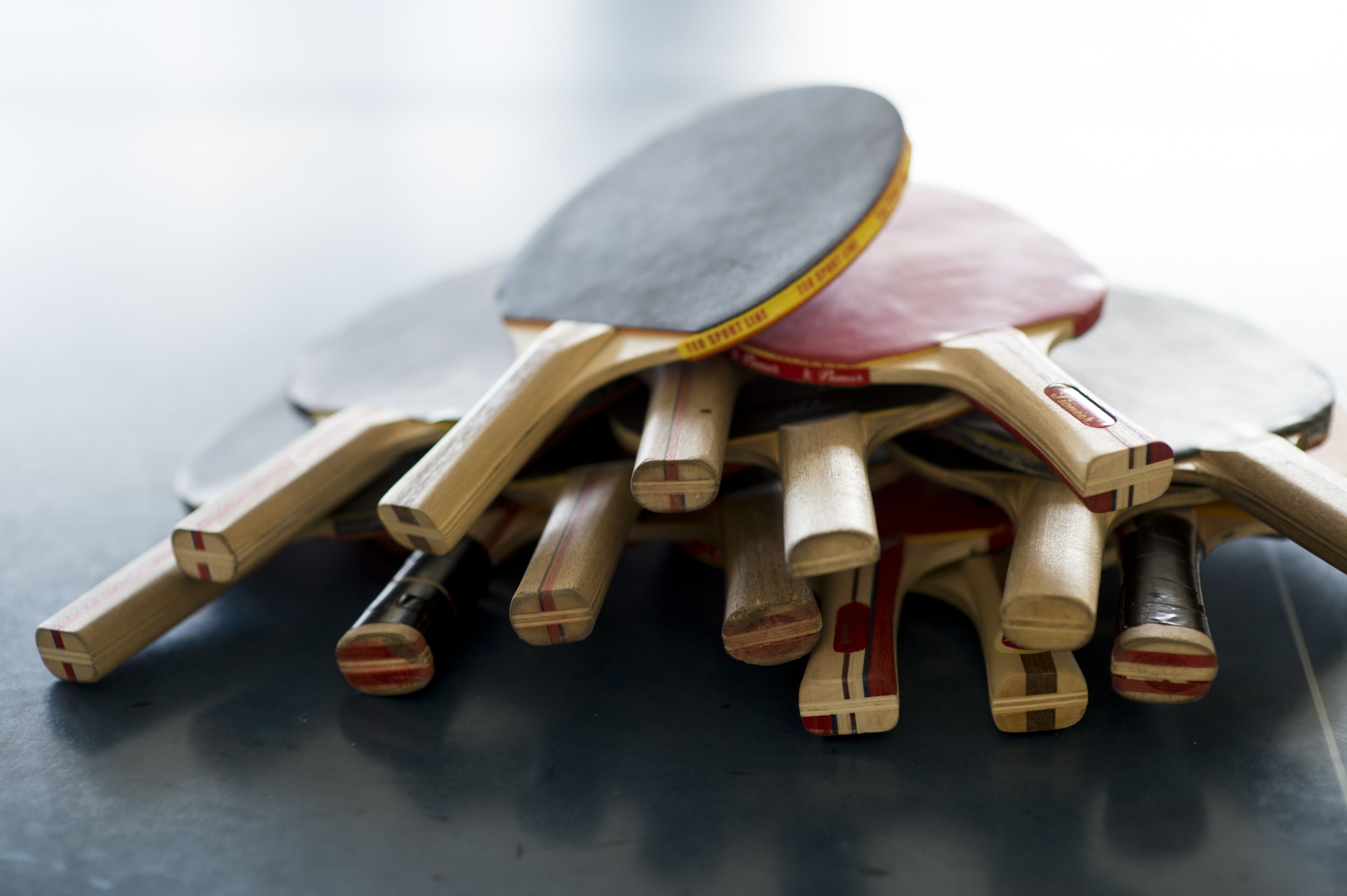 Een verzameling houten tafeltennispaddles en een paddle op een donkere ondergrond.