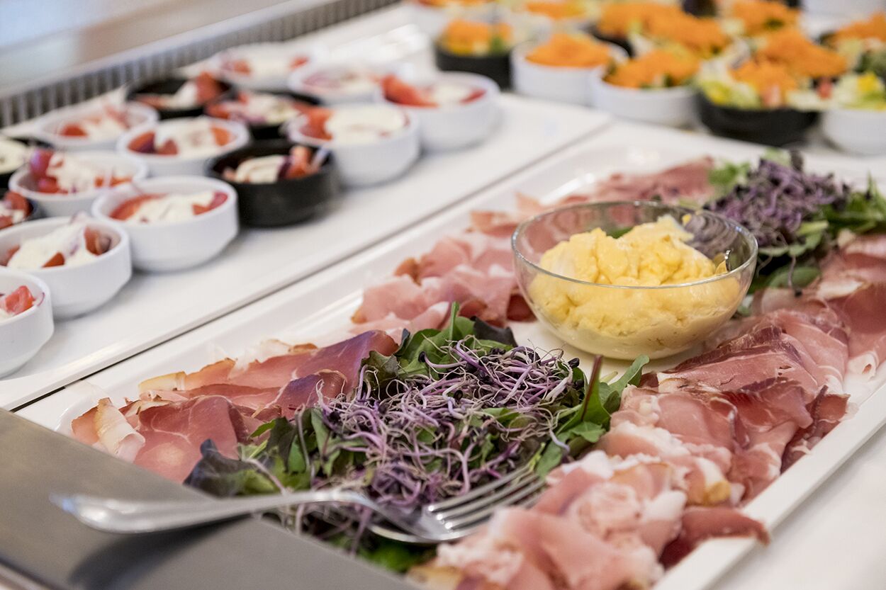 A buffet with various food items including meats, salads, and dips.