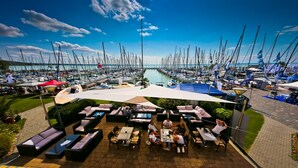 Un puerto deportivo con numerosas embarcaciones amarradas, zonas de estar al aire libre con sombrillas y una vista despejada del agua.