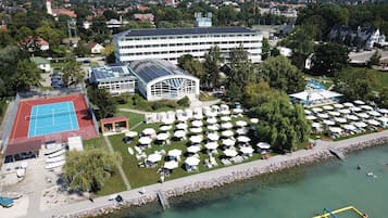 Enjoy lakeside relaxation with a tennis court, outdoor seating area, and tranquil water views surrounded by lush greenery.